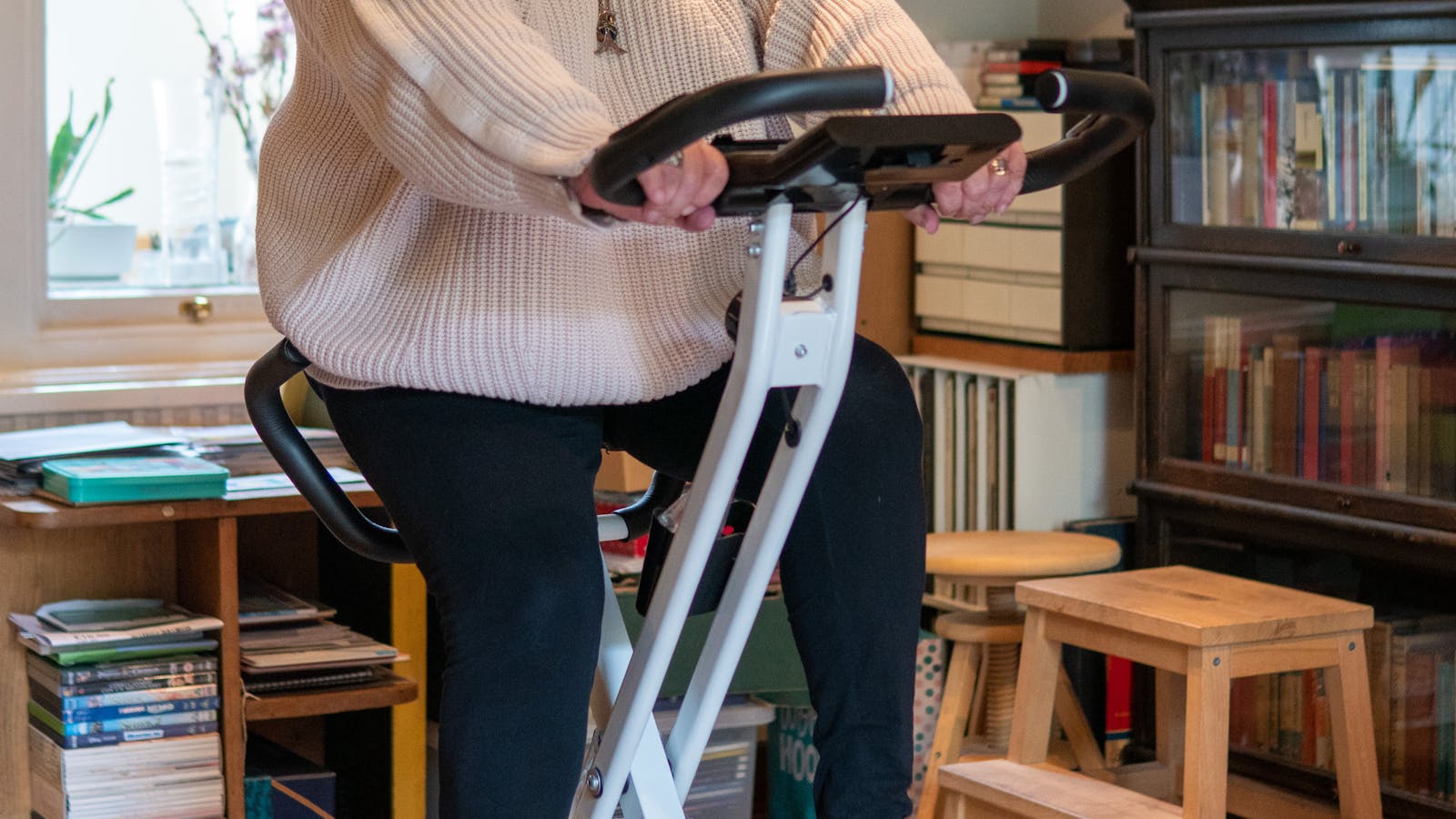 Woman using a stationary bike in a cozy home setting.