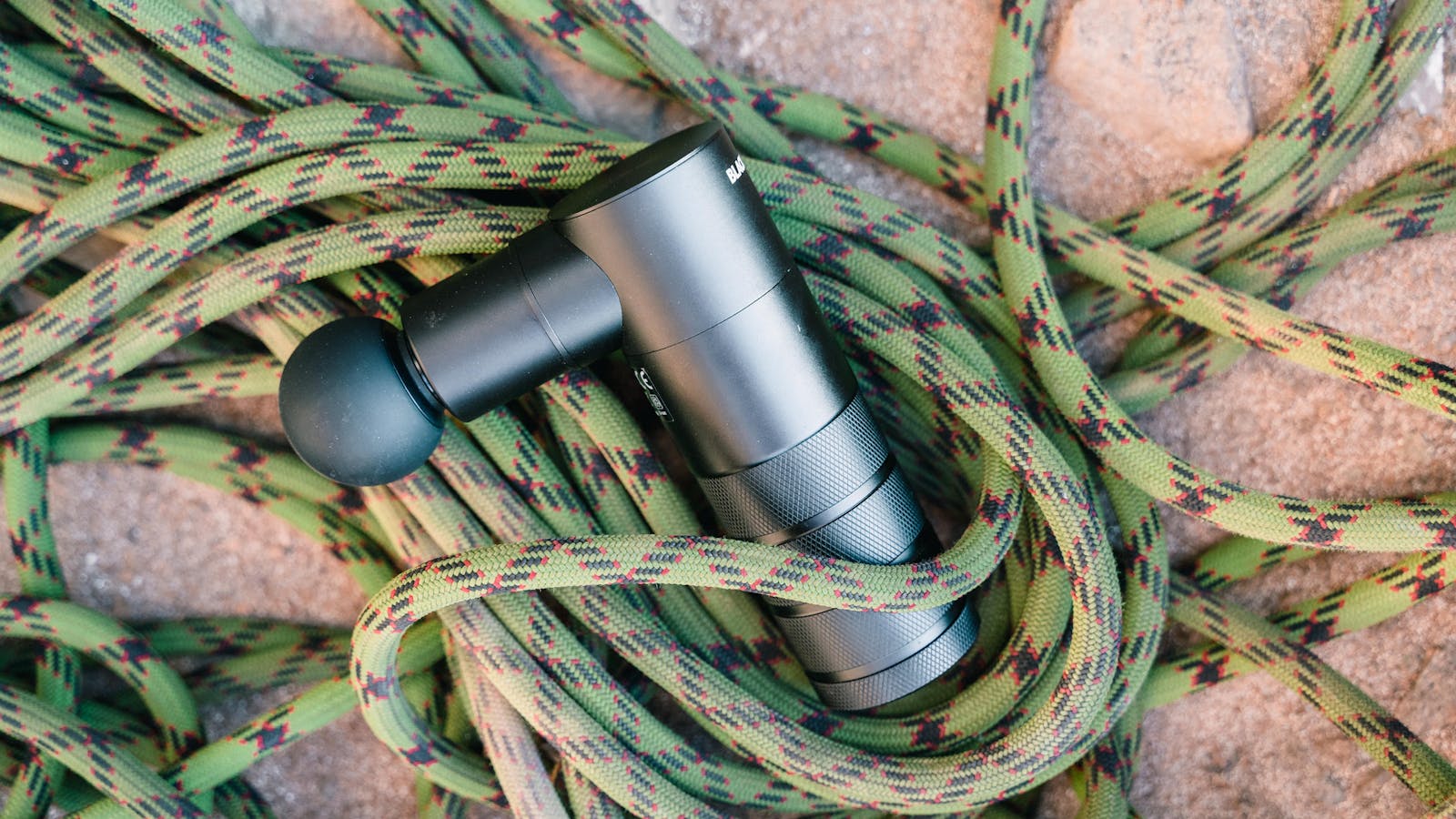 Massage gun placed on climbing rope as a recovery tool.