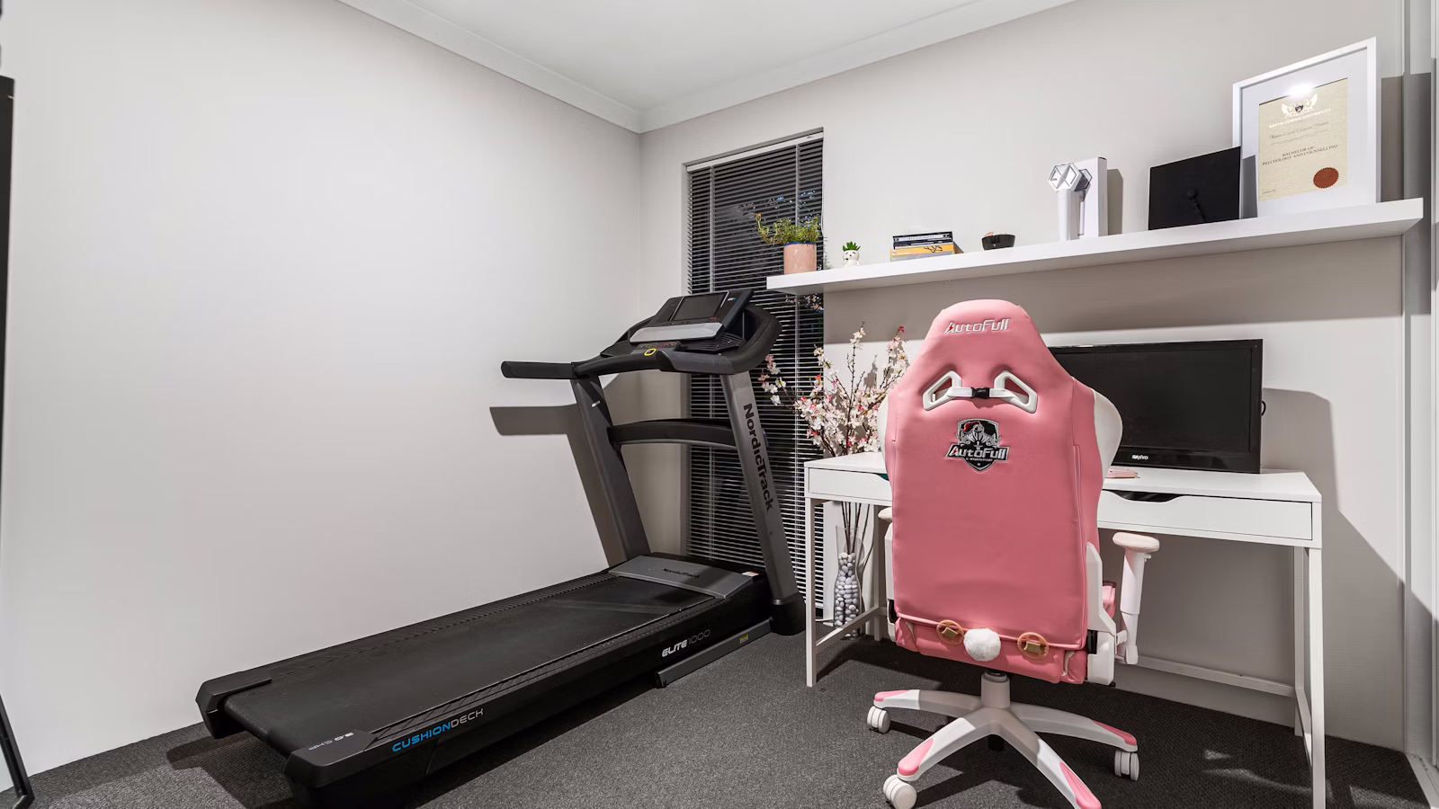 Treadmill beside a desk in a compact home office.